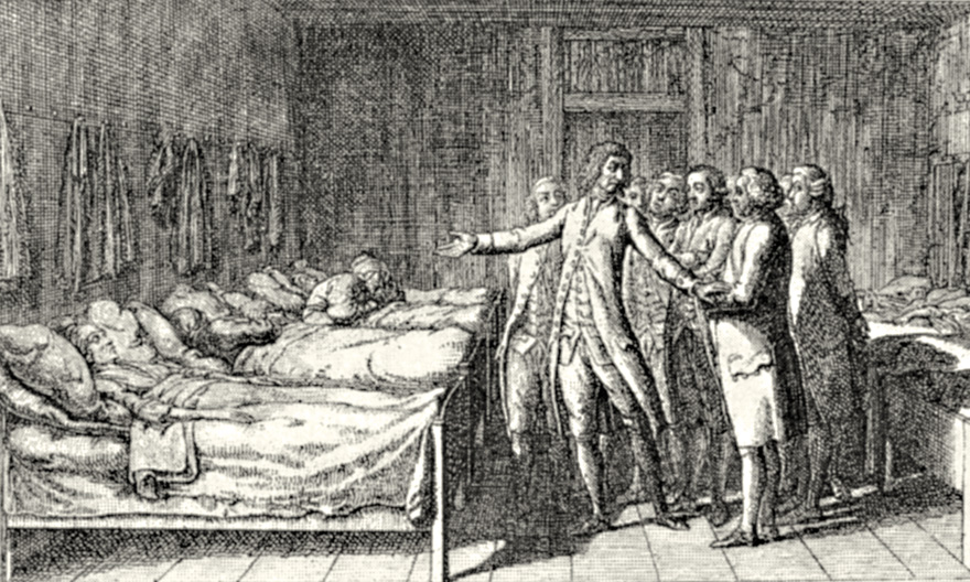 Männer stehen in einem Krankensaal mit Krankenbetten