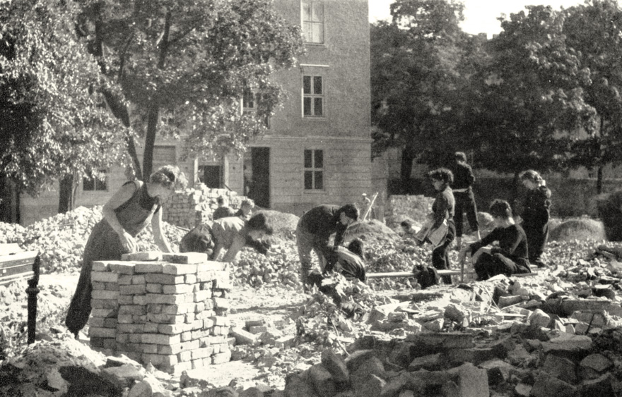 Menschen sammeln Ziegel inmitten von Ruinen